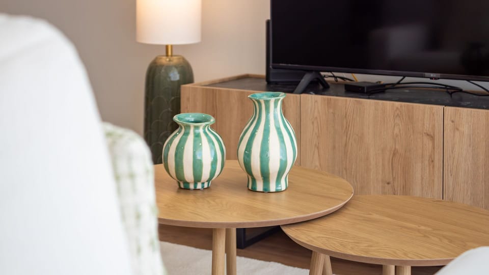 Discover charming details that enhance the living room's cozy ambiance, from the elegantly nested coffee tables to the textured lamp and decorative vases. These thoughtful touches make the space feel like a welcoming home away from home.