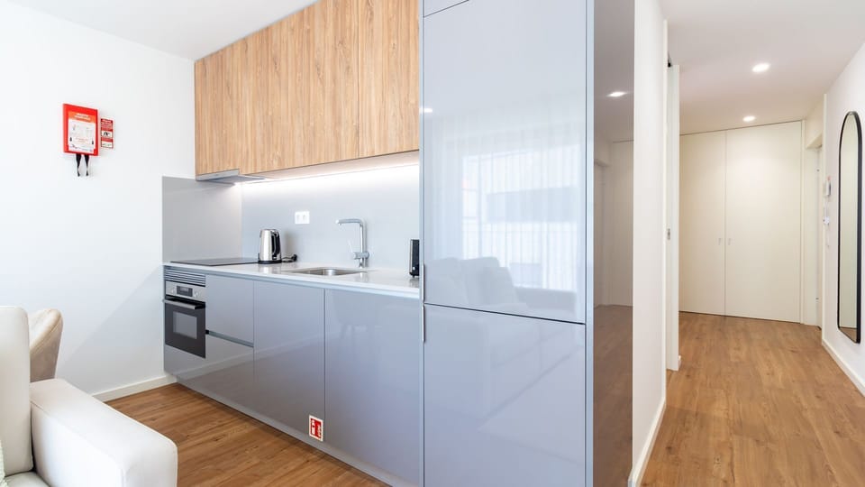Step into a sleek, open-plan space where a modern kitchenette invites you to prepare light meals, brightly lit by under-cabinet lights and natural light filtering through from the living area. The efficient design offers everything you need for a comforta
