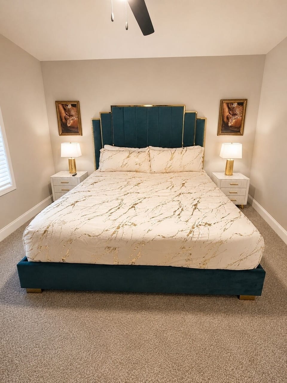Elegant king bedroom with teal velvet bed and warm, cozy lighting