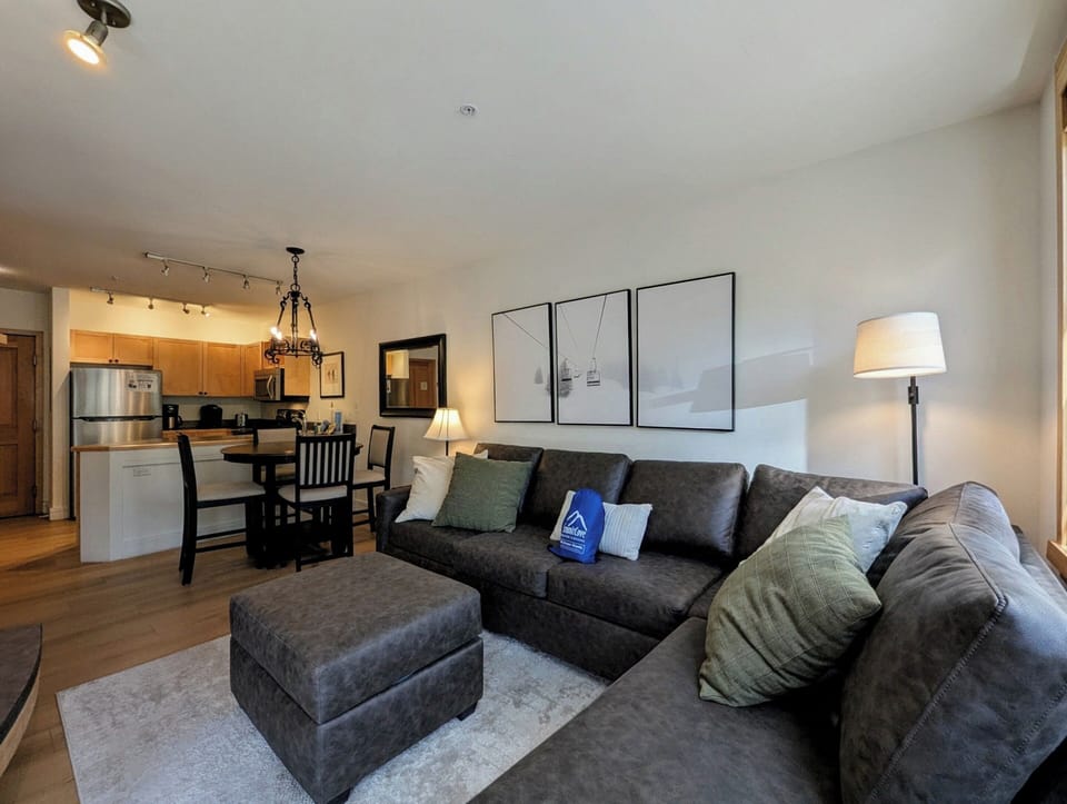 Sink into the plush sectional and unwind in your open-concept retreat, where warm lighting, modern decor, and a fully equipped kitchen create the perfect home base.