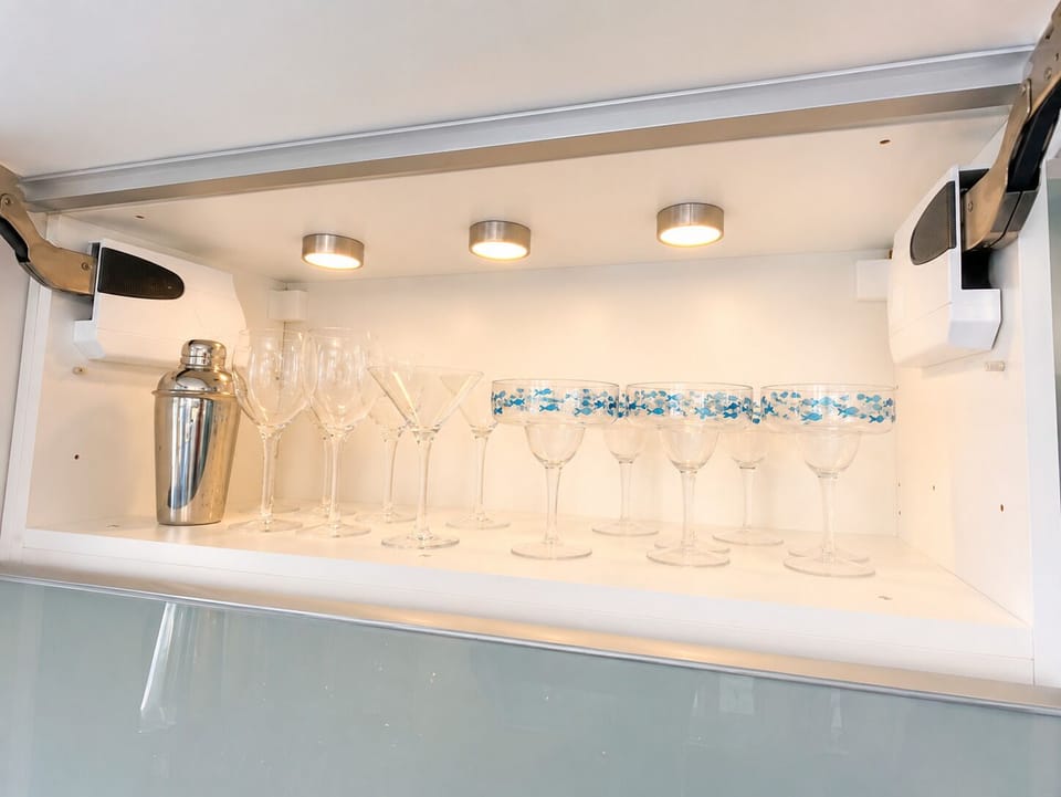 Lit glass shelves with a selection of glasses for your cocktail enjoyment.