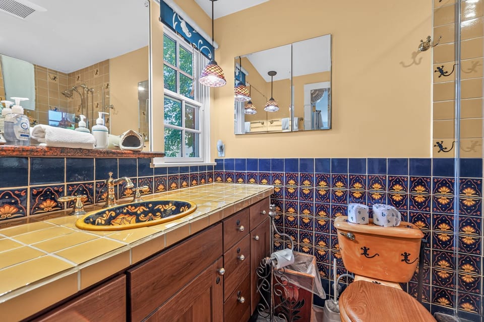 Vibrant bathroom featuring patterned blue wall tiles, a tiled vanity, and a painted sink.
