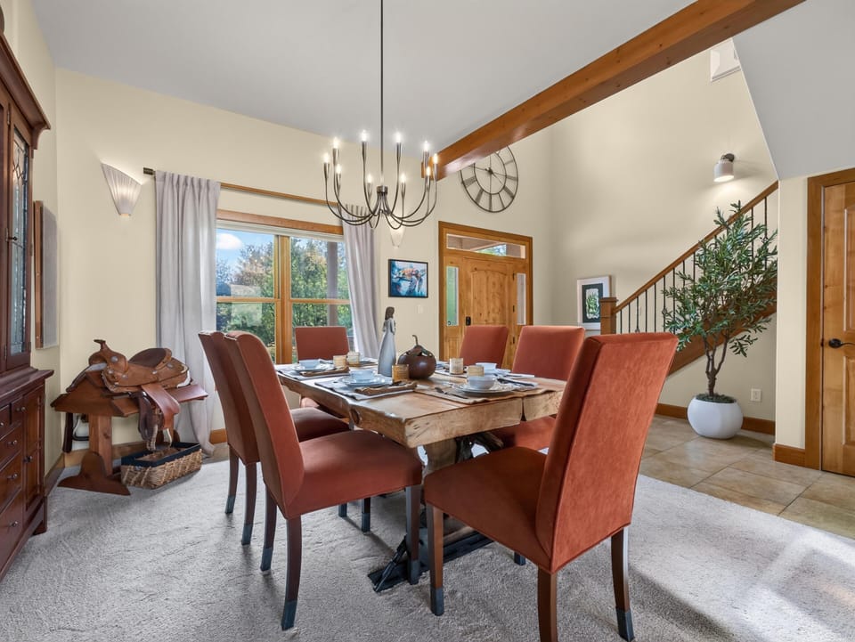 Rust-colored upholstered chairs encircle a live-edge wood dining table beneath a modern black chandelier.