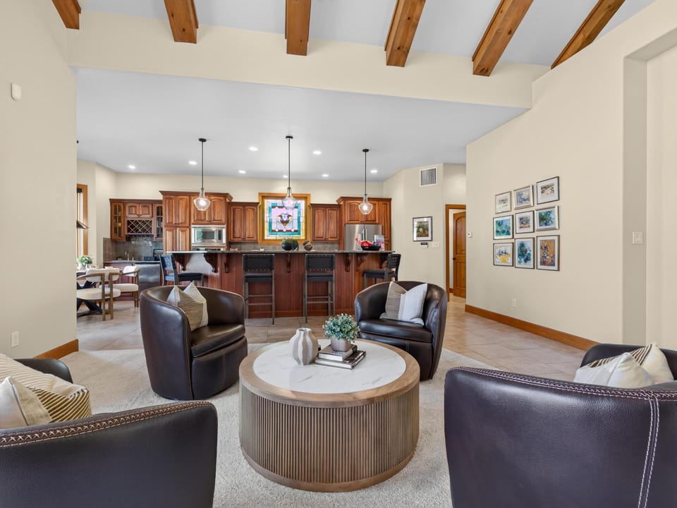 Leather swivel chairs encircle a round wood-and-marble coffee table in the open living area with vaulted wood beams.