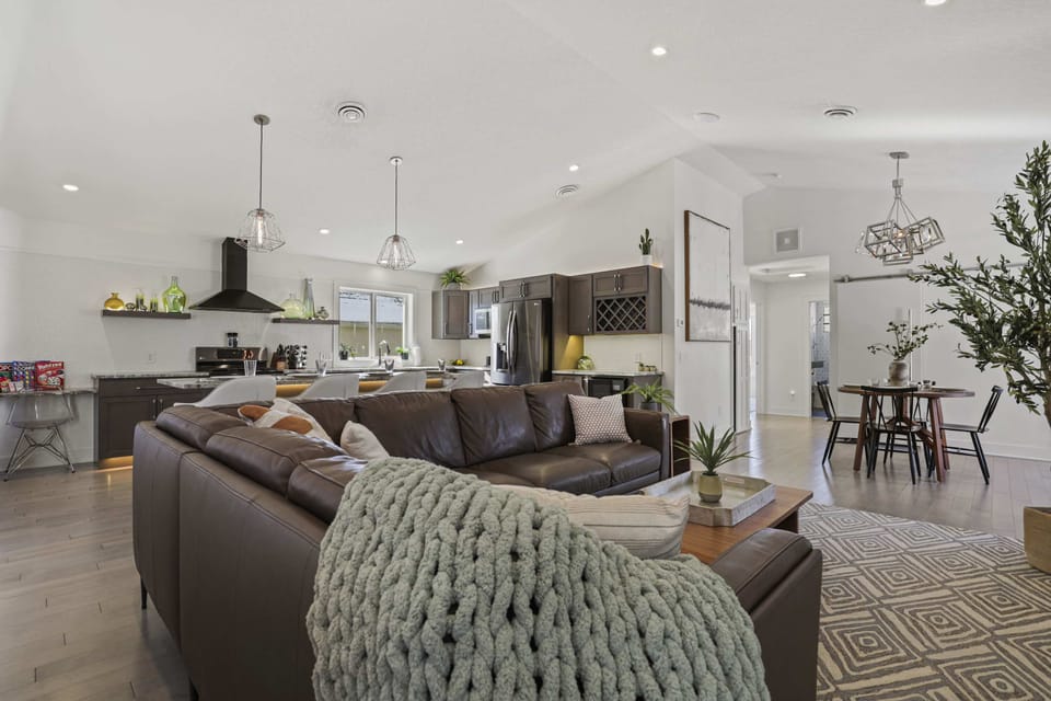 Open concept living area with high end leather couch, gas fire place, and 65" smart TV.
