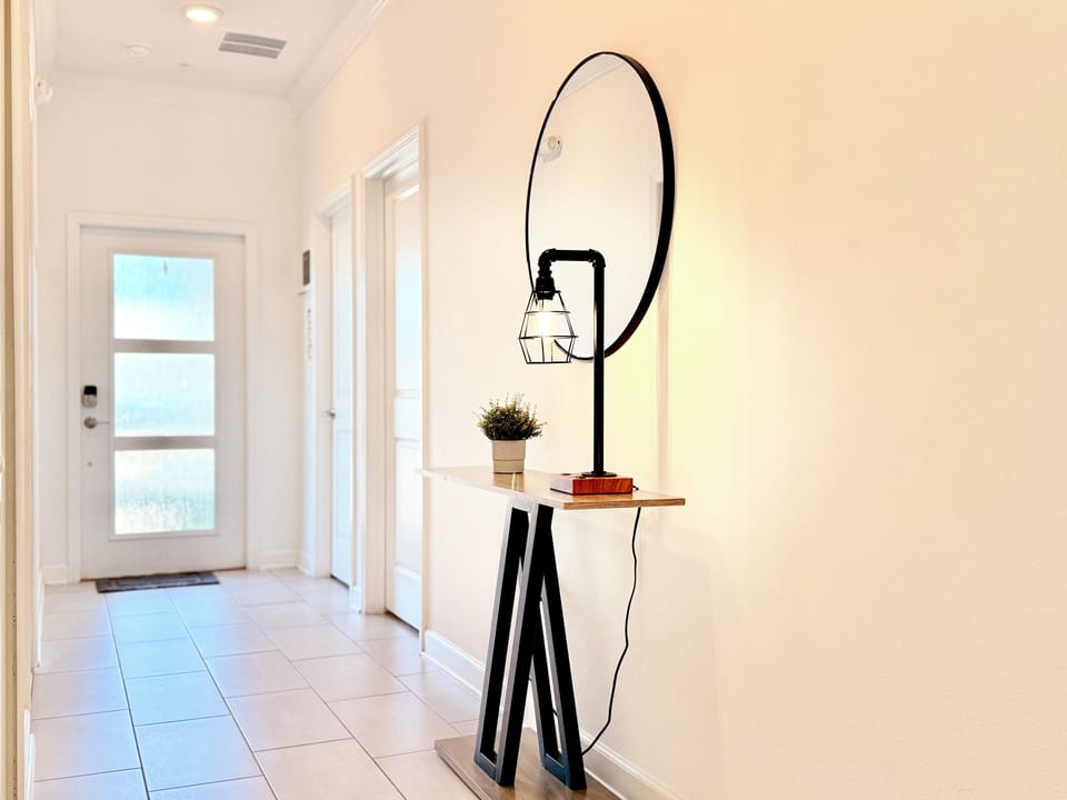 Bright entry hallway featuring a modern pipe lamp and circular mirror.