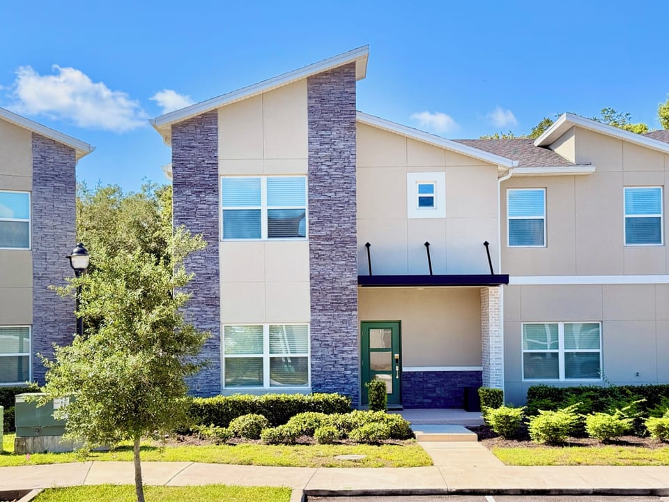 Modern two-story townhome exterior with stone accents and manicured lawn.