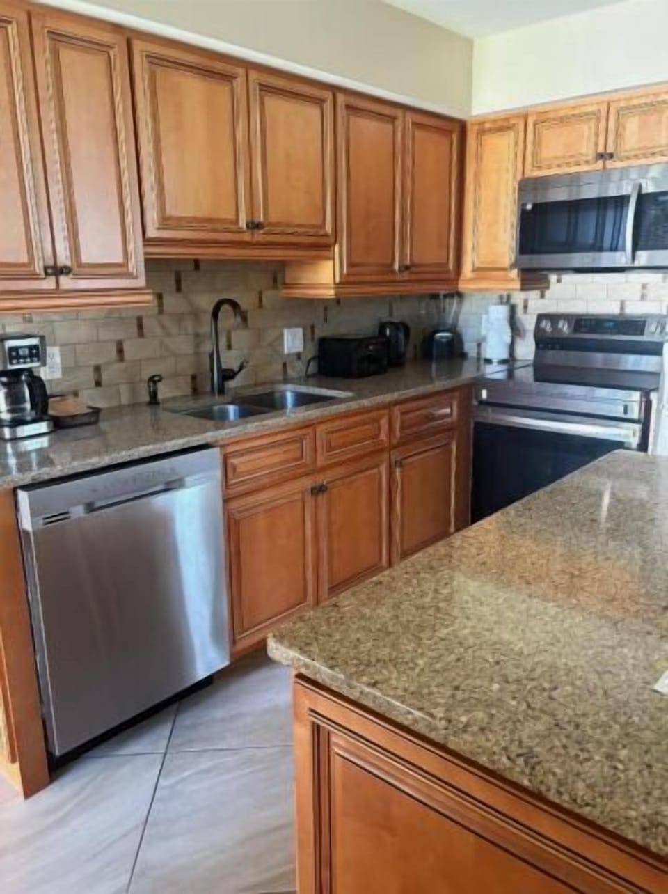 Spacious granite kitchen with stainless appliances and warm wood cabinets
