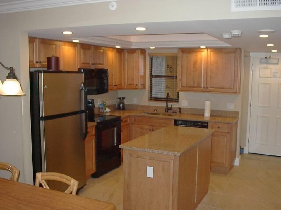 Bright full kitchen with granite counters, island, and warm wood cabinets