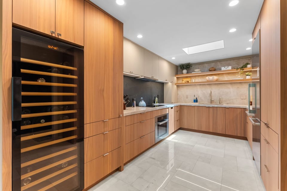 Modern chef’s kitchen with wine fridge, skylight, and warm wood finishes