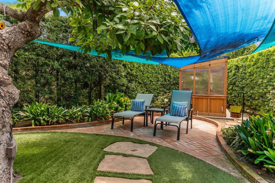 Private shaded garden patio with loungers and lush greenery