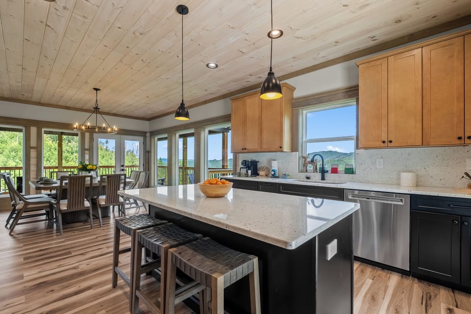 Fully equipped kitchen featuring a spacious island, bar seating, stainless steel appliances, and an adjacent dining area.