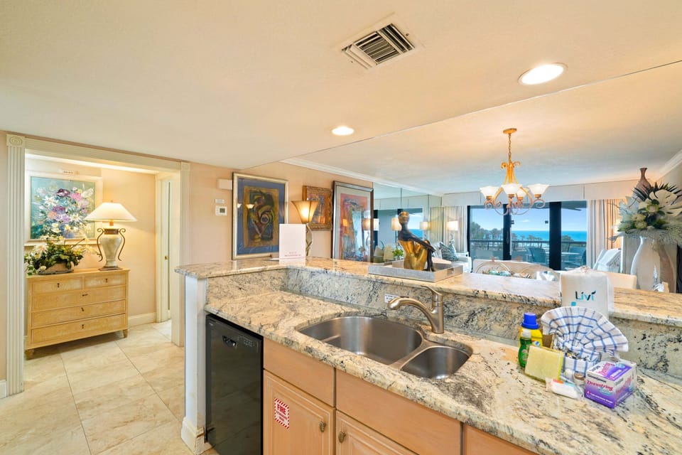 Enjoy a fully equipped beachfront condo kitchen with granite countertops and an open view toward the Gulf front living area and balcony.