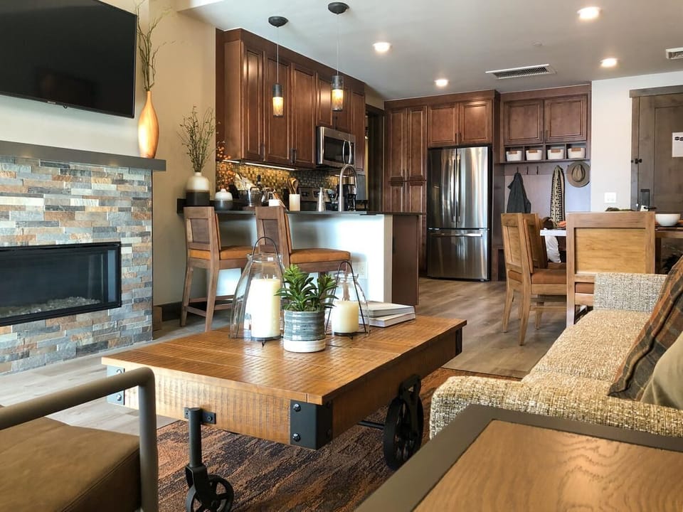 Cozy open-concept living space with fireplace, TV, and stylish full kitchen