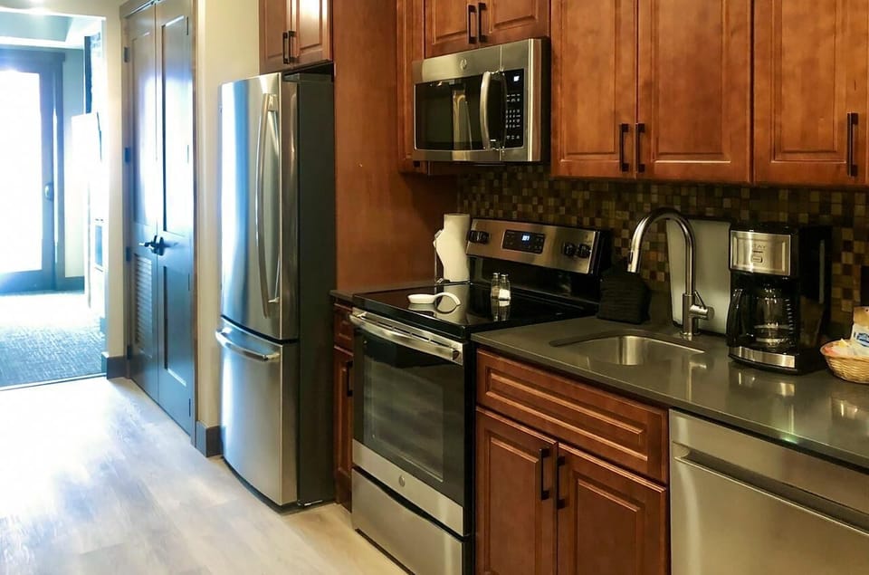 Modern kitchen with stainless appliances, coffee maker, and warm wood finishes