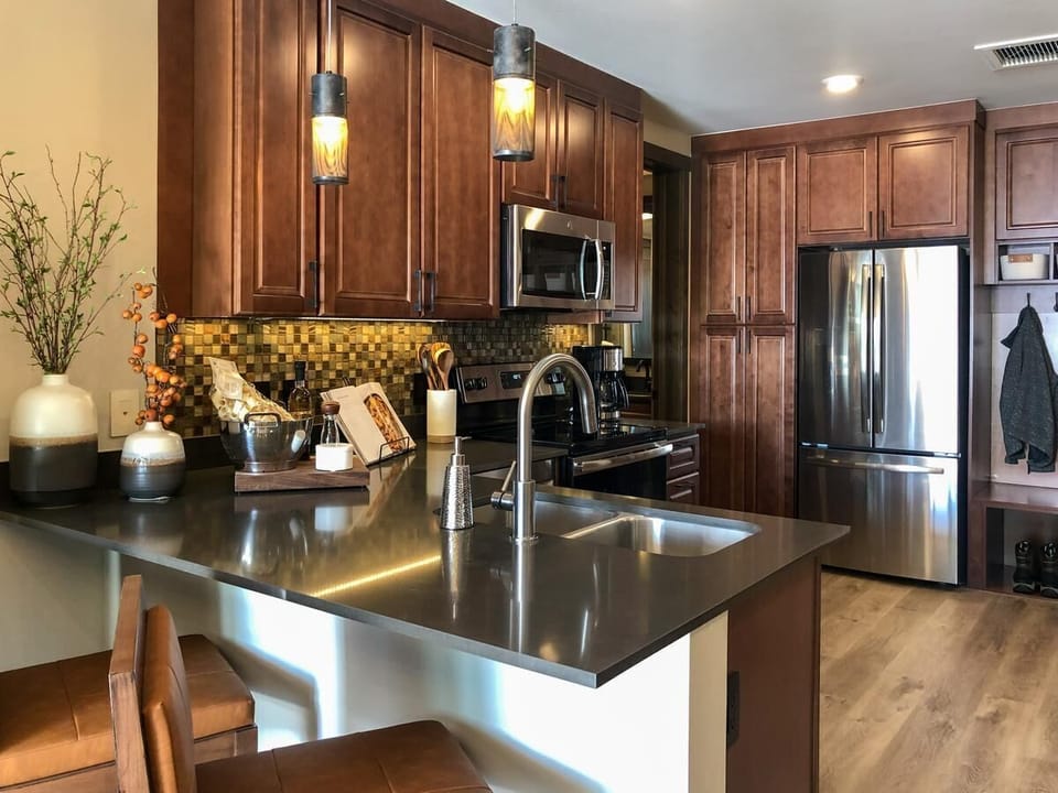 Modern kitchen with island seating, stainless appliances, and warm finishes