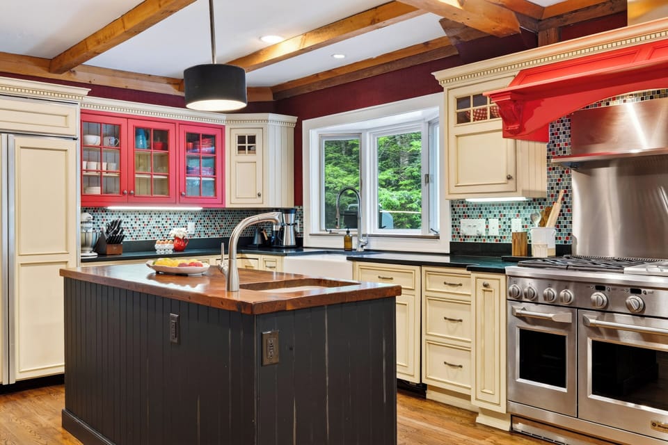 Kitchen island with prep sink, gas range, and warm cabinetry