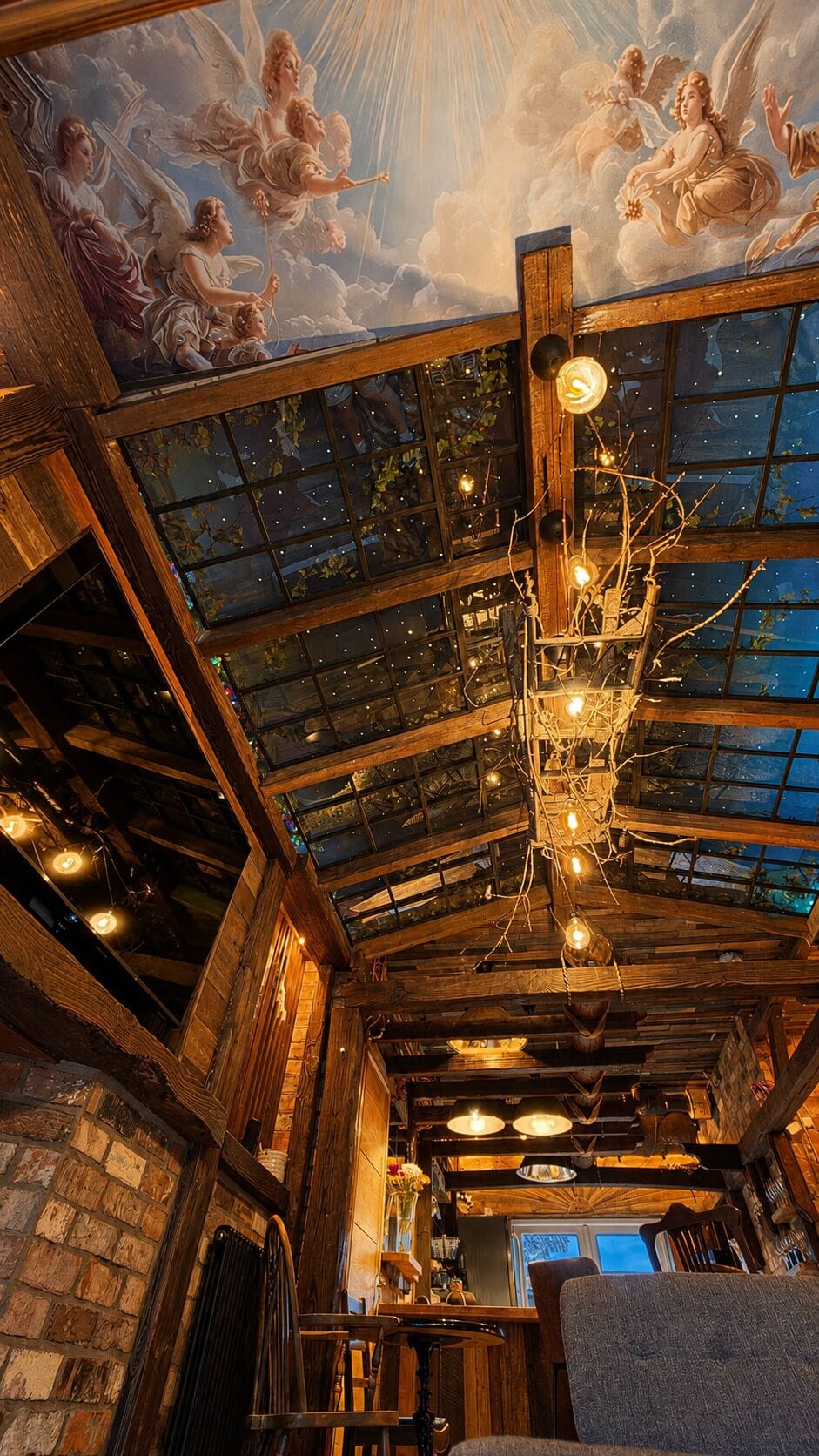 A fully handmade ceiling showcases reclaimed wood, a starry glass roof, and a distinctive branch chandelier above the sofa bed.