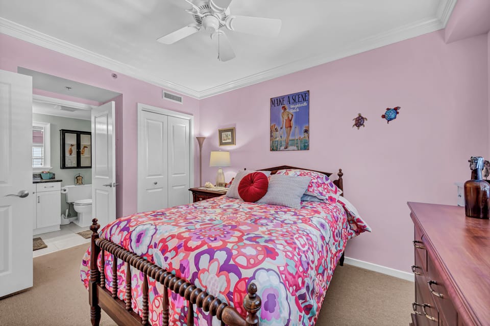 Drift off in your cheerful bedroom, where soft pink walls, a cozy bed, and coastal accents create the perfect escape after sun-filled days.