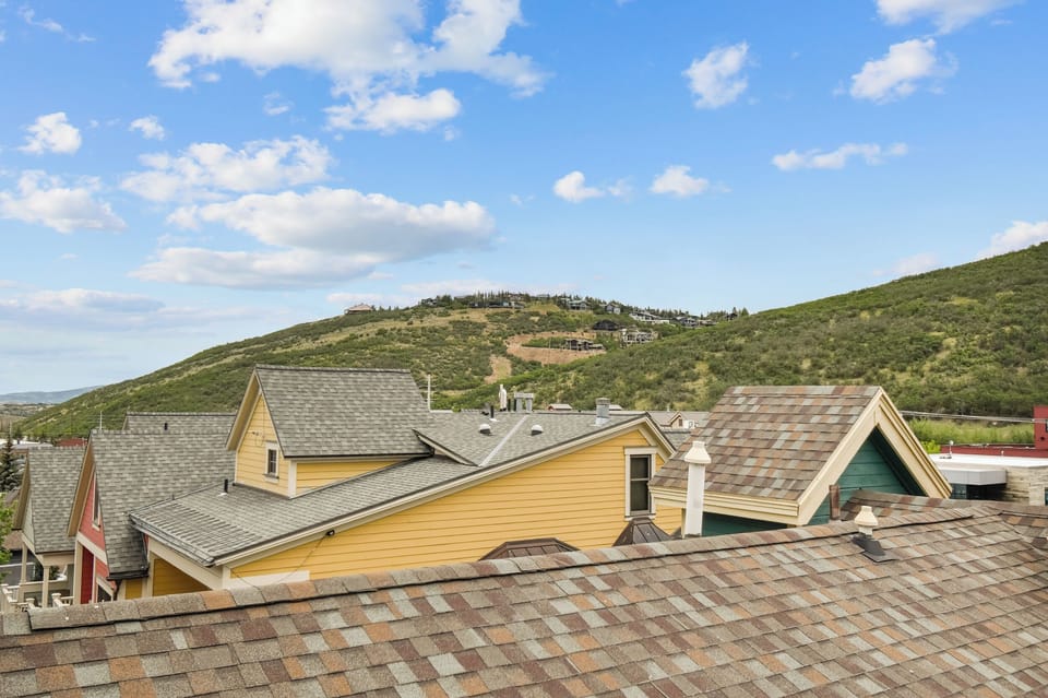 Elevated hillside setting with rolling terrain and neighboring homes visible in the distance, framing the property's natural surroundings and mountainous backdrop.