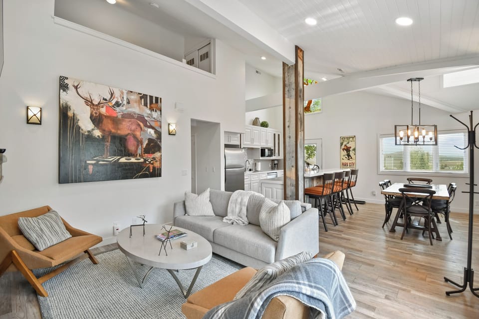 Relax in this airy open-concept living space, where modern comfort meets rustic charm with soaring ceilings, natural wood accents, and seamless flow to the dining and kitchen areas.