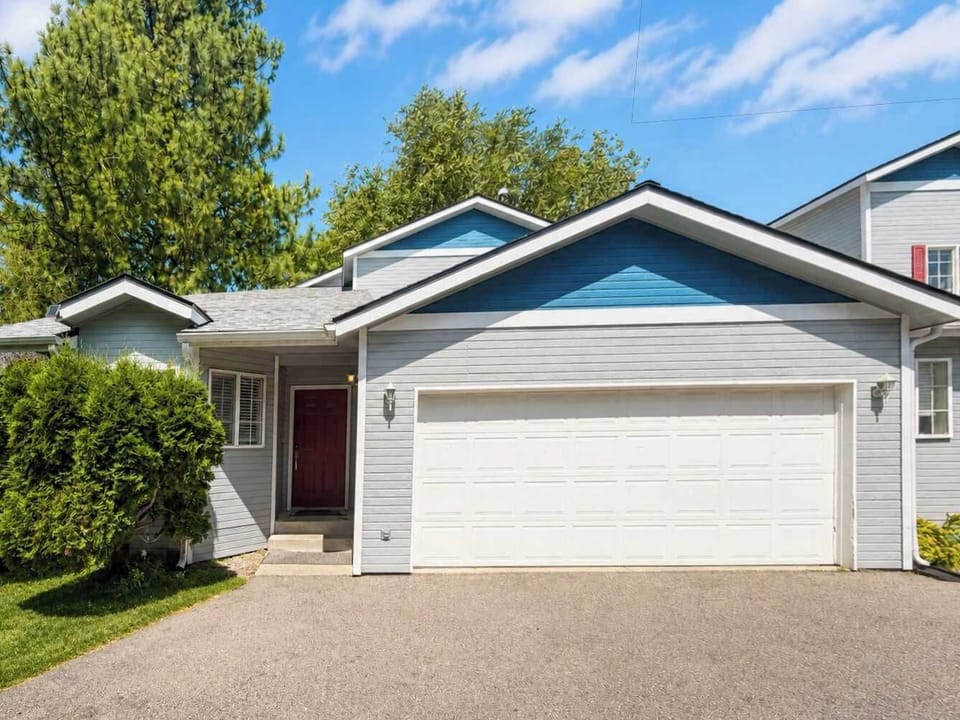 Front exterior with an attached two-car garage, paved driveway, mature landscaping, and a recessed entry.
