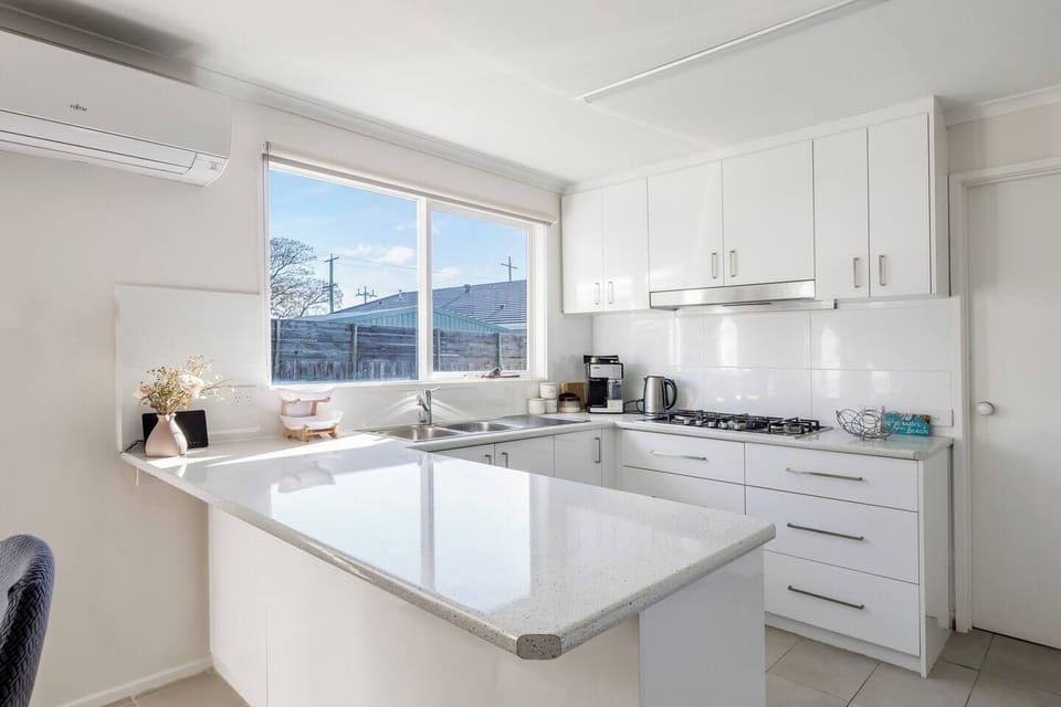 Whip up beachside meals in the crisp white kitchen, featuring a gas cooktop, generous bench space, and plenty of natural light.