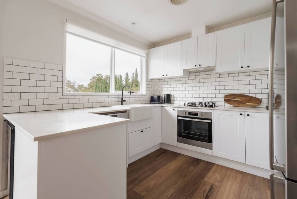 Prepare meals with ease in the full kitchen, featuring gas cooking, an oven, fridge, dishwasher, coffee machine, a deep farmhouse sink, and spacious bench space for easy meal prep.