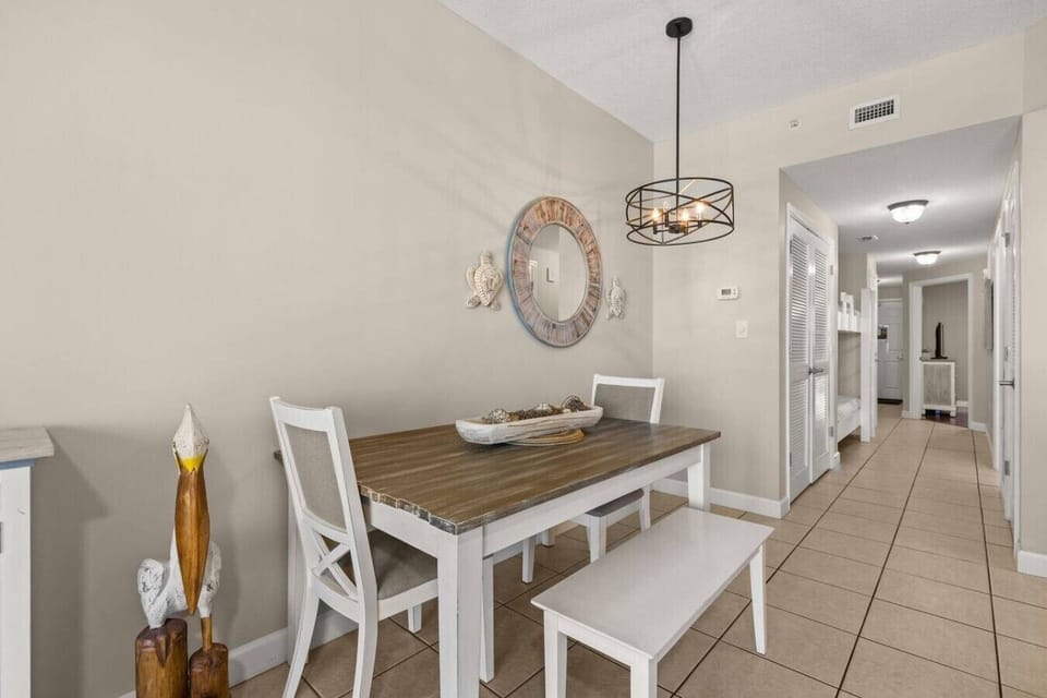 Gather for meals at this coastal dining table featuring bench seating, white chairs, a statement pendant light, and nautical wall décor.