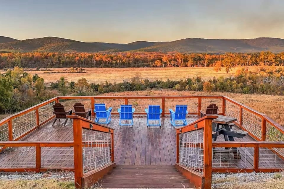 Expansive elevated deck with Adirondack seating and panoramic mountain and river views.