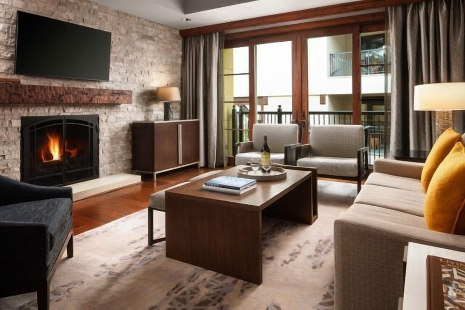 Cozy mountain-style living room with fireplace, TV, and private balcony