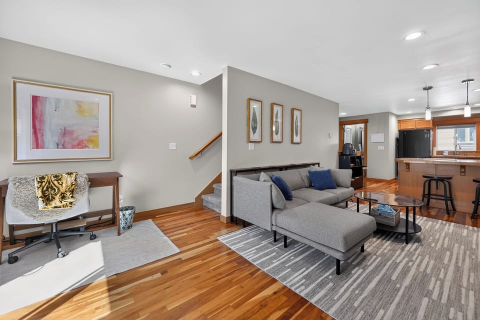 Bright open living area with sectional, workspace, and kitchen bar seating
