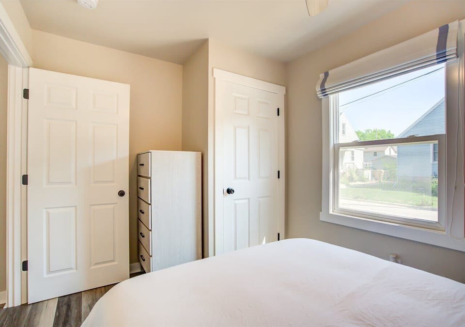 Bedroom with a compact dresser and full closet for easy clothing and personal storage. Large window fills the space with natural light, creating a bright and organized retreat.