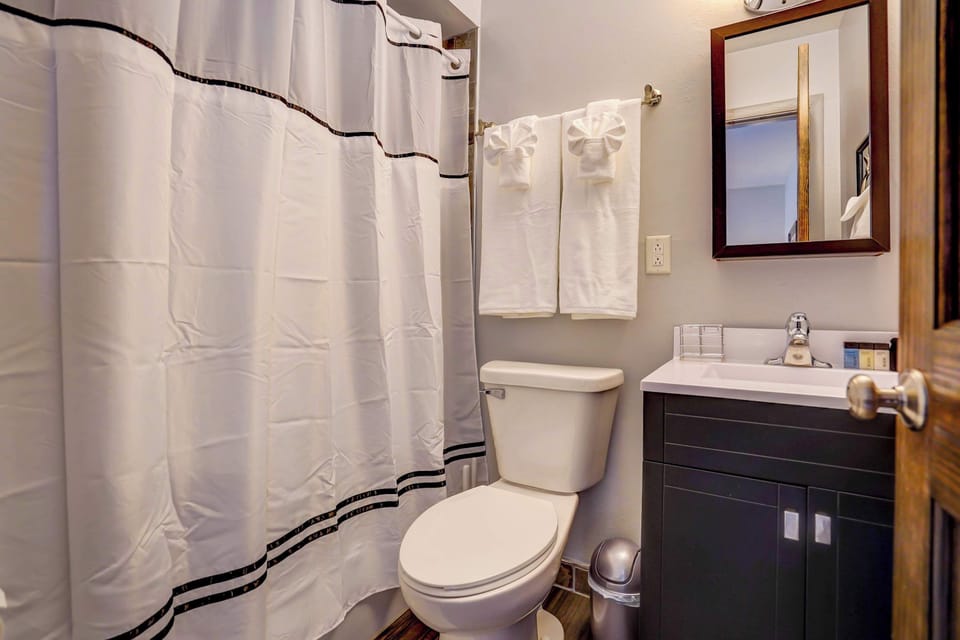 Clean and practical bathroom featuring a full shower-tub combo, fresh towels, and complimentary toiletries for a comfortable, worry-free stay.
