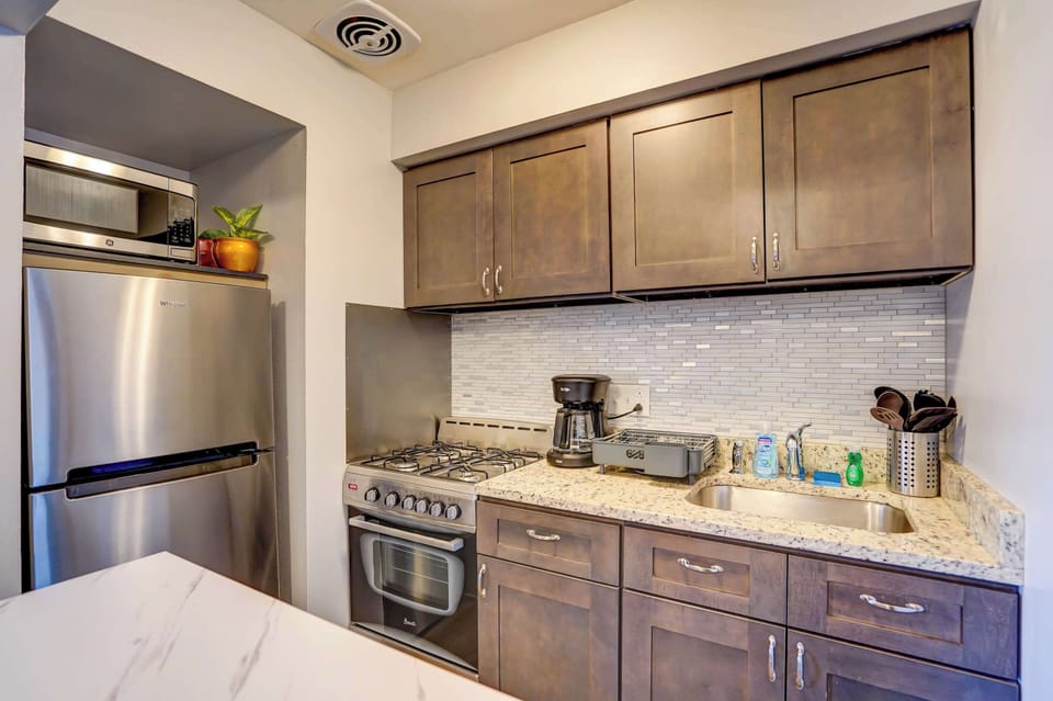 Modern kitchen equipped with stainless steel appliances, full cookware set, and ample counter space—perfect for preparing meals or brewing your morning coffee with ease.