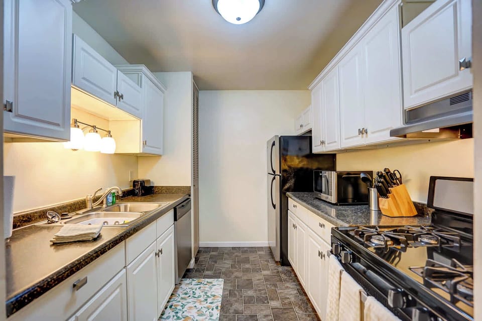 Fully equipped kitchen featuring stainless steel appliances, sleek black countertops, and bright white cabinetry—perfect for cooking and entertaining with ease.