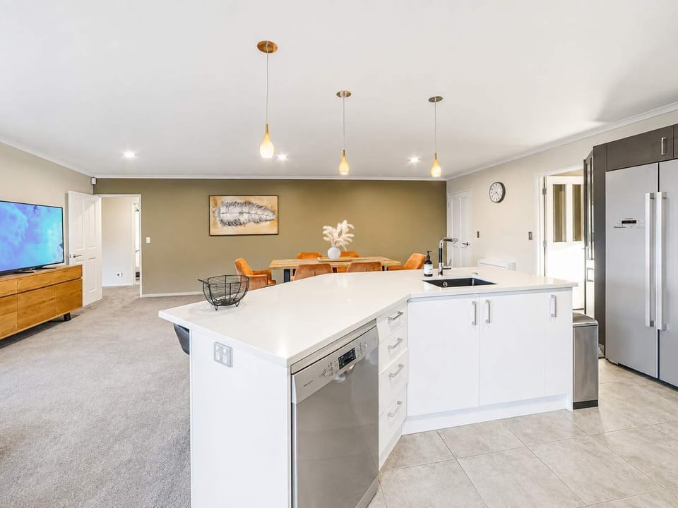 Large modern kitchen with a central island, breakfast bar seating, ample cabinetry and open-plan access to the dining area.