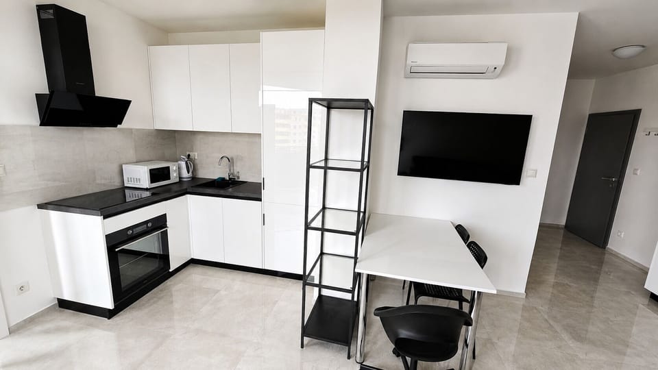 Modern open kitchen with dining area, A/C, and wall-mounted TV