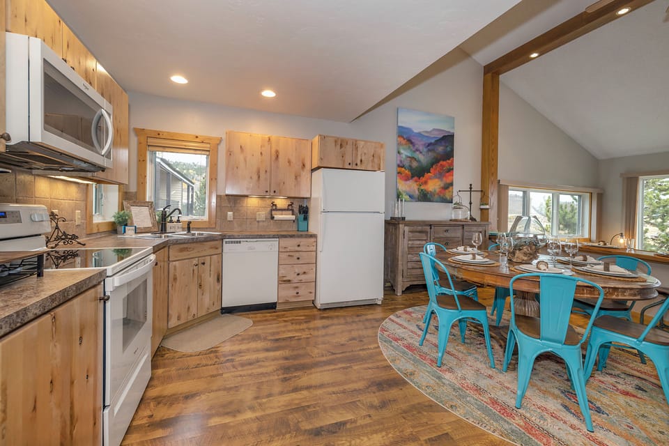 Gather around the rustic dining table after a day of adventure. Your open kitchen flows into the dining space, with warm wood tones and natural light creating the perfect spot to share meals together.