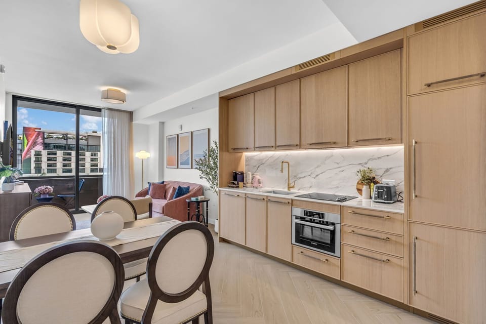 Open-concept kitchen and dining area with premium appliances, warm wood cabinetry and a stylish dining set — perfect for meals in