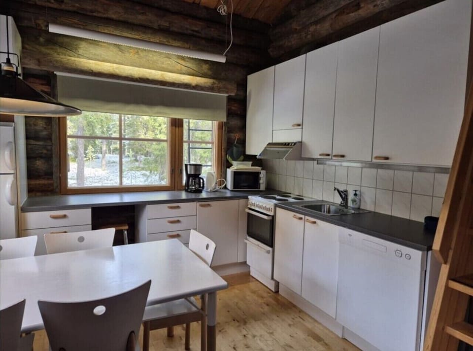 Open-plan kitchen with an electric stove, microwave and coffee maker, and a dining table with chairs.