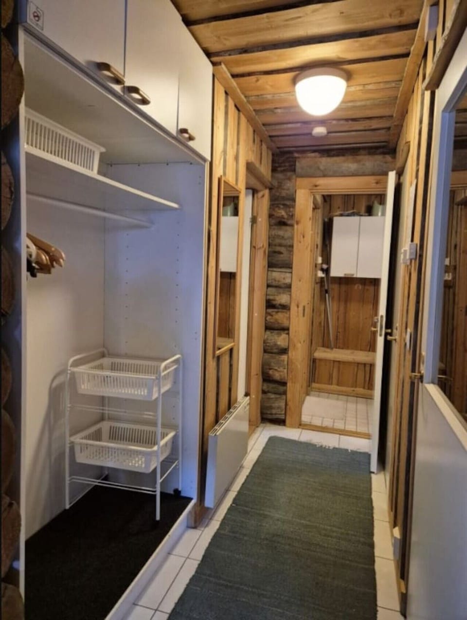 Dressing room with hanging space and shelving next to the washroom and sauna.