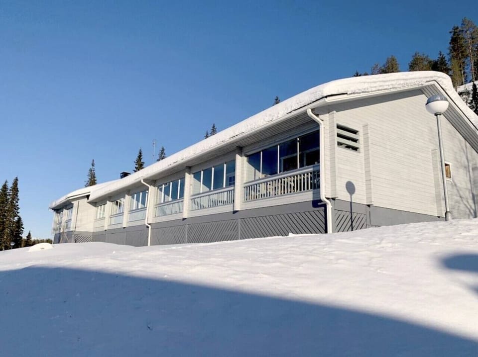 Exterior of the log terraced building with snow-covered surroundings in winter.