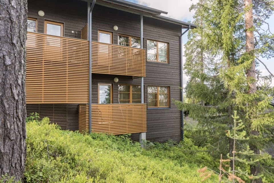 Exterior view of the apartment building with private balconies among the pines.