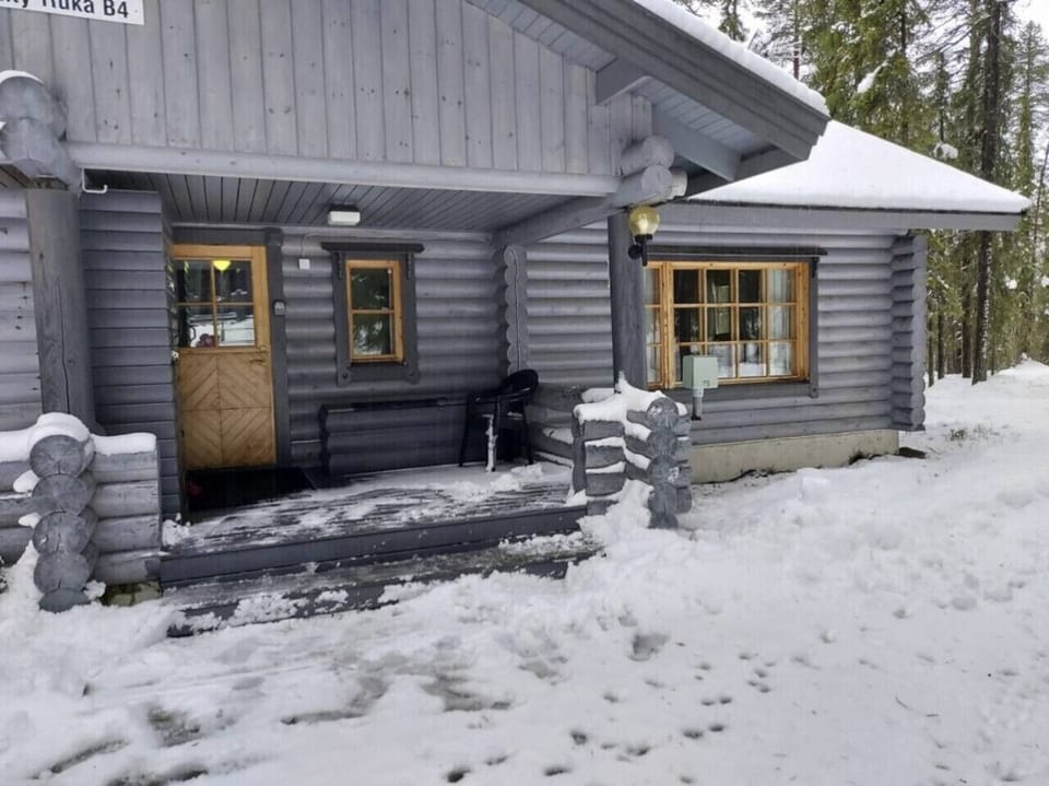 Entrance to the log building with a covered porch, pictured in winter.