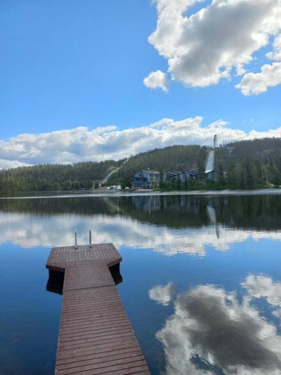View across the lake from the pier towards the forested hillside on the opposite shore.
