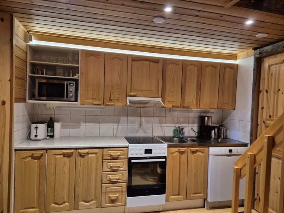 Fully equipped kitchen with an electric stove and oven, microwave, dishwasher, coffee maker and kettle.