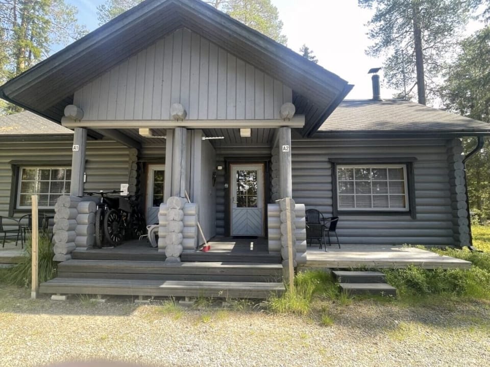 Exterior view of the log cabin with a covered porch entrance and outdoor seating.