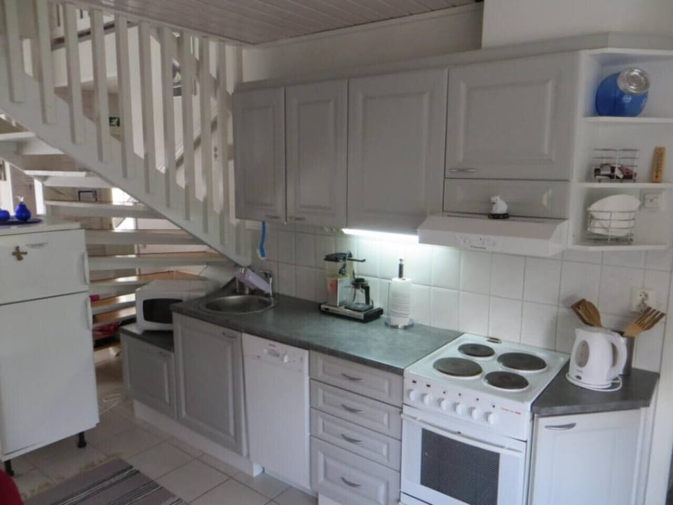 Fully equipped kitchen with an electric stove, oven, dishwasher, coffee maker and kettle.