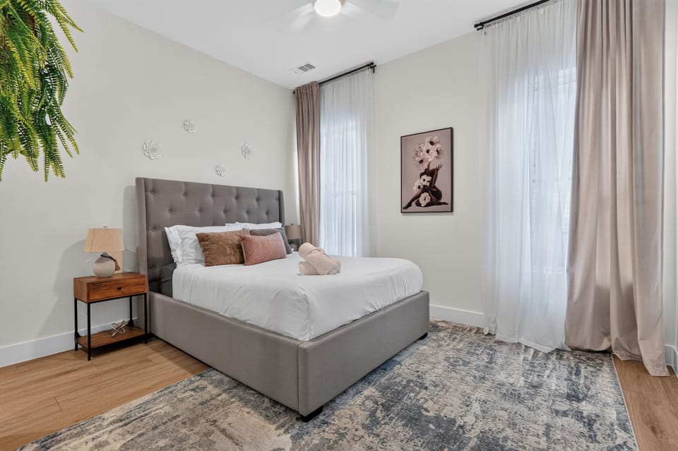 Bright, elegant bedroom with tufted bed and tall sunlit windows